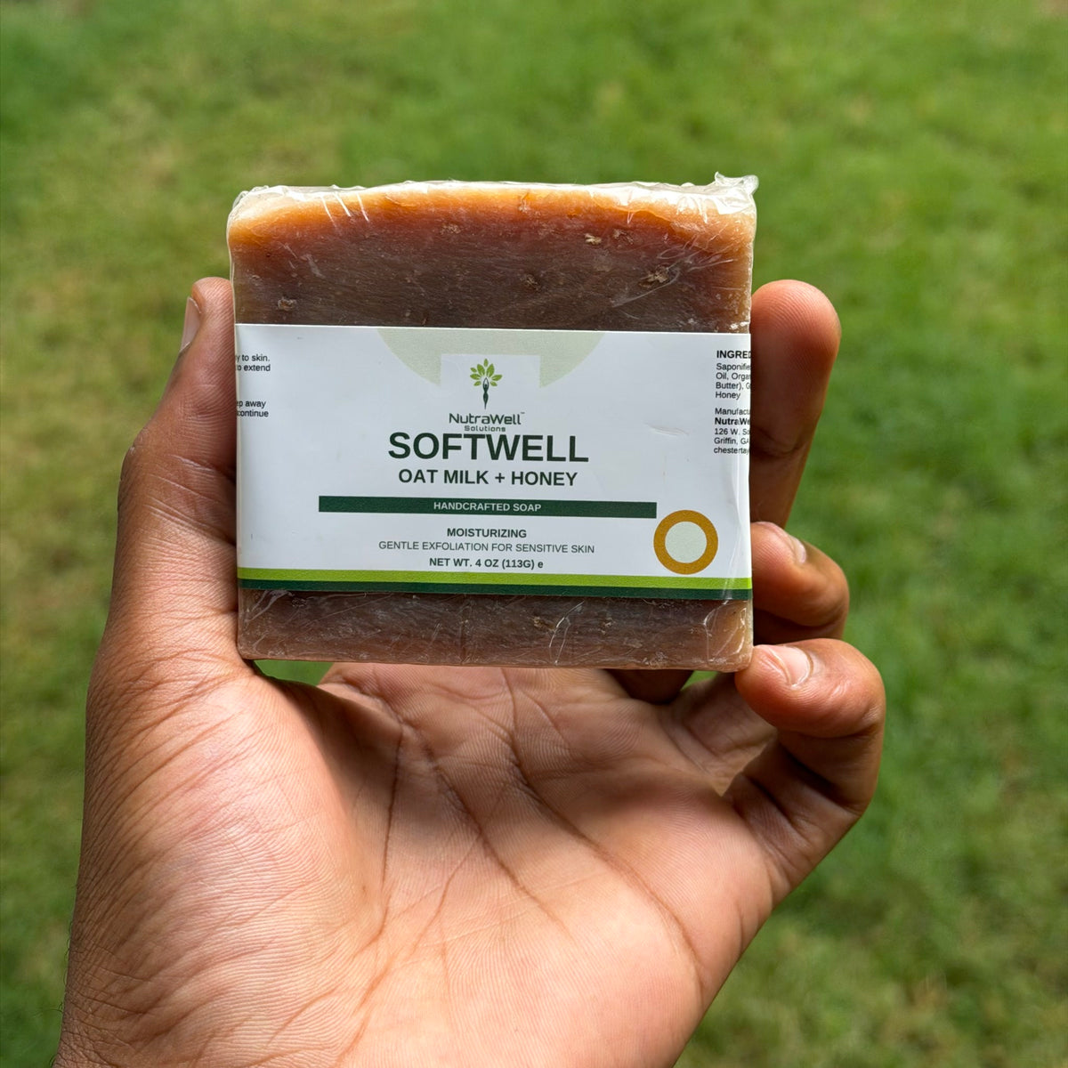 SoftWell Oat Milk + Honey handcrafted soap bar held in hand outdoors, showing bar size