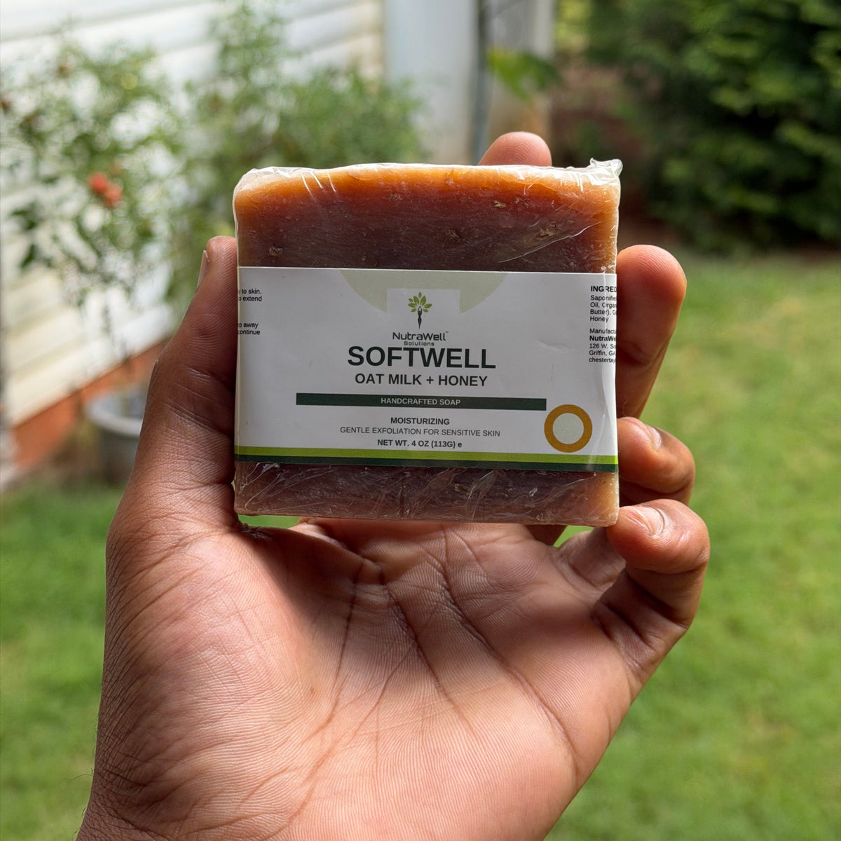 SoftWell Oat Milk + Honey 4 oz soap bar held in hand, label showing ingredients and net weight