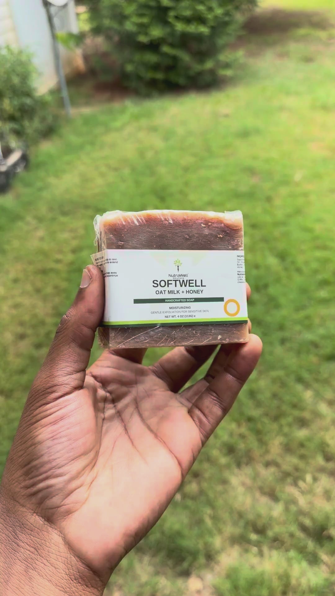 Video: SoftWell Oat Milk + Honey soap bar turned in hand outdoors, showing the label and bar size