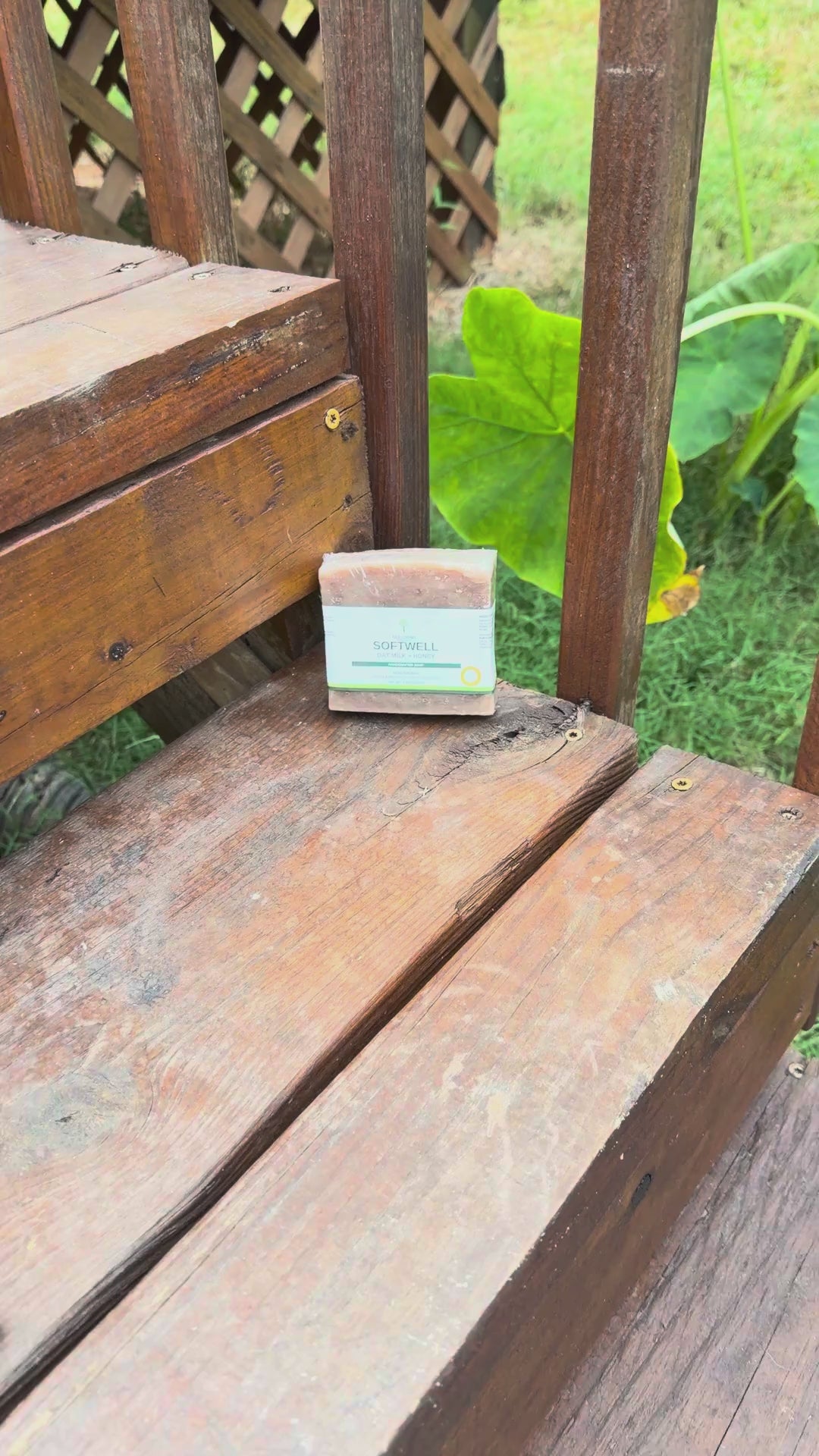 Video: SoftWell Oat Milk + Honey soap bar on a wooden garden bench with green leaves