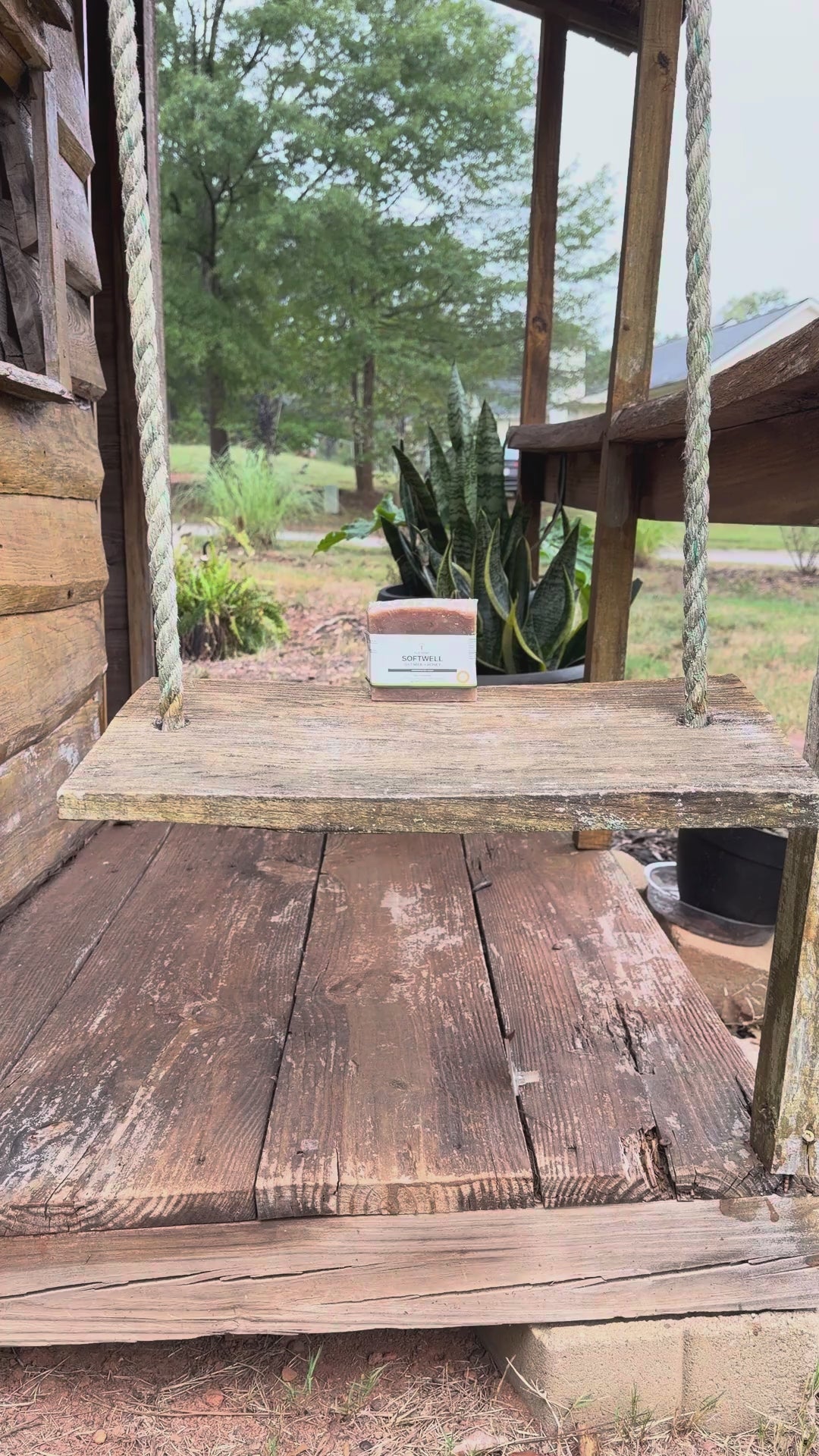 Video: camera moves in on a SoftWell Oat Milk + Honey soap bar sitting on a wooden porch swing