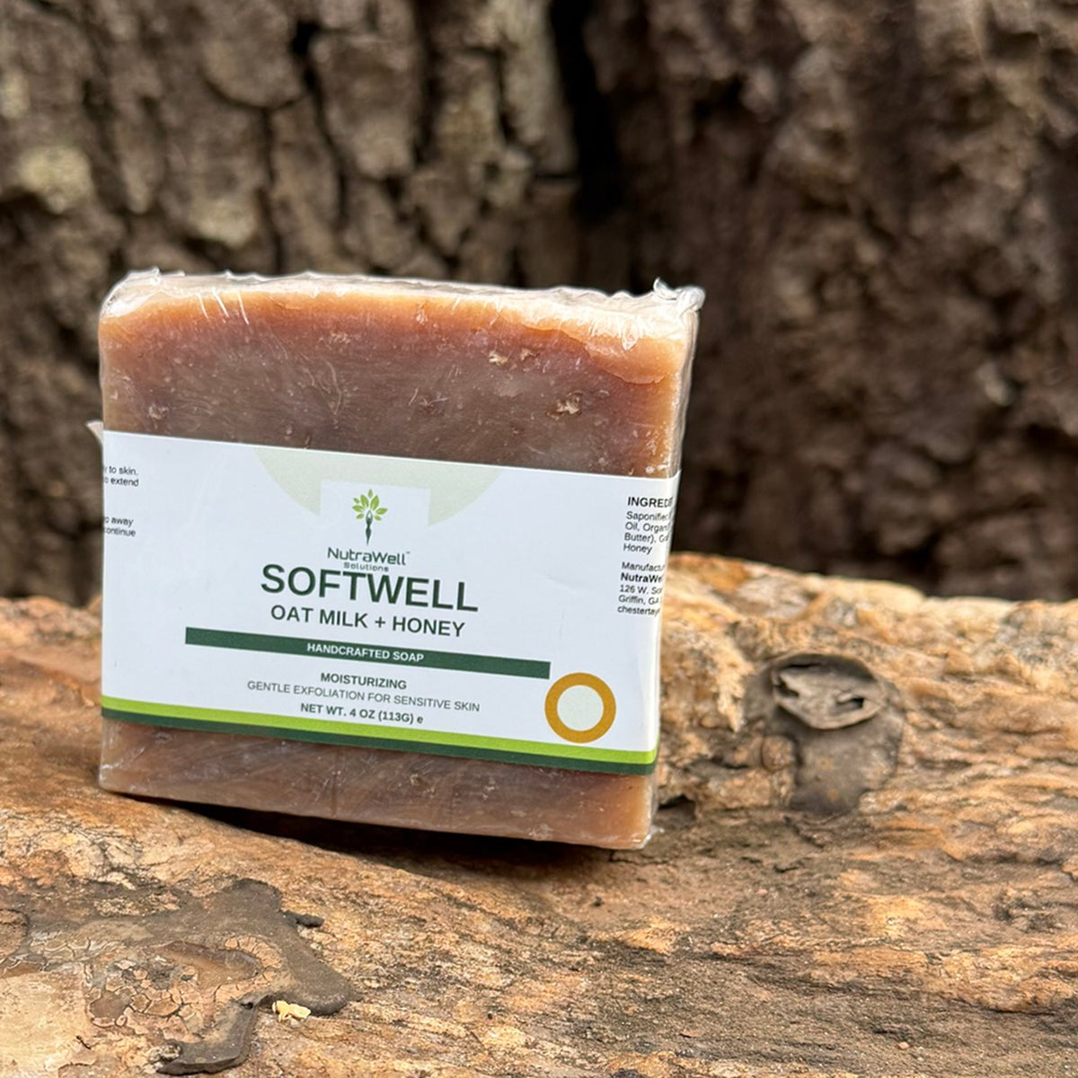 SoftWell Oat Milk + Honey 4 oz bar outdoors on stone, oat flecks visible through the wrapper